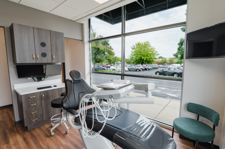 Dental exam room with a chair, monitor, and cabinets.